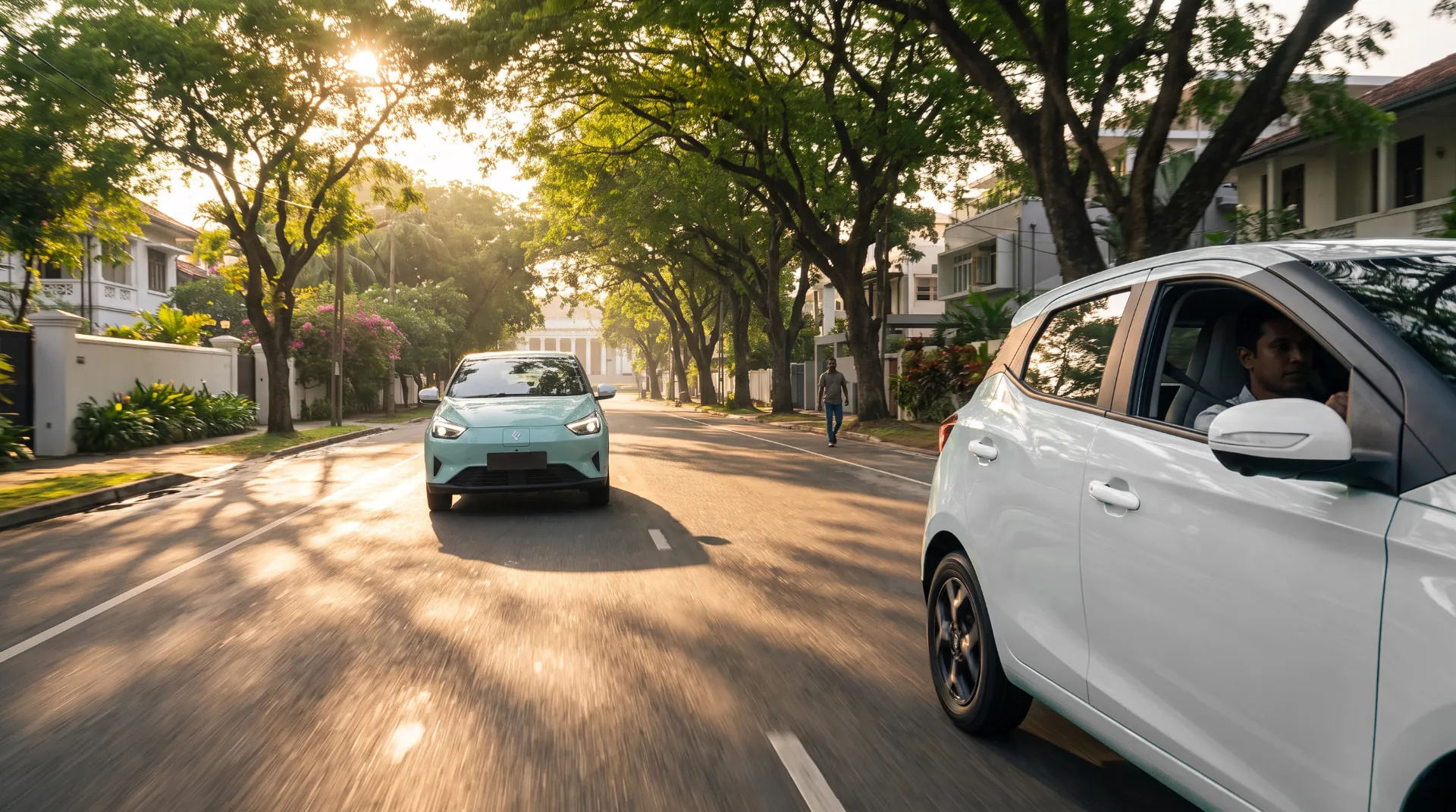 Mint-green and white JMEV EV3 cars driving along a tree-lined city avenue